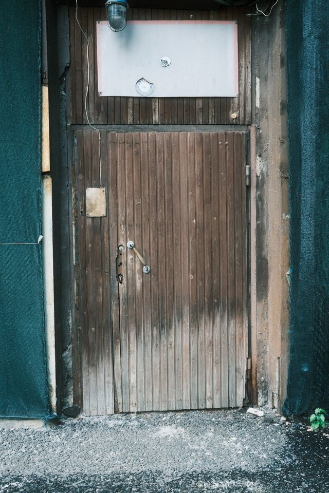 A weathered wooden door with a blank pale panel and a hanging light above it in a dark Moscow doorway.