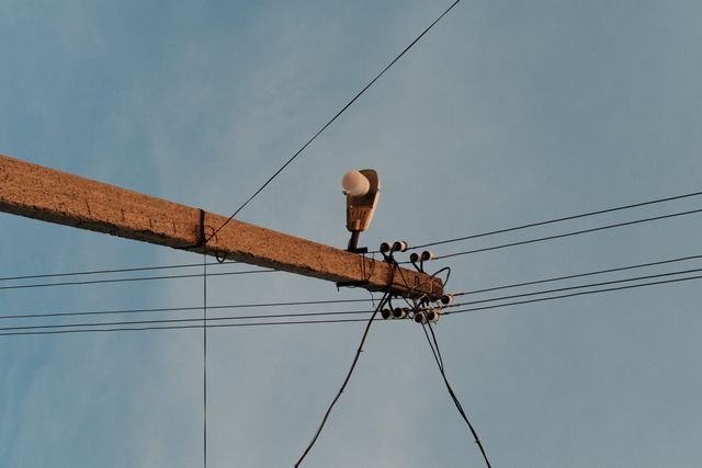 古びた横腕に碍子と複数の架空電線が取り付けられている。