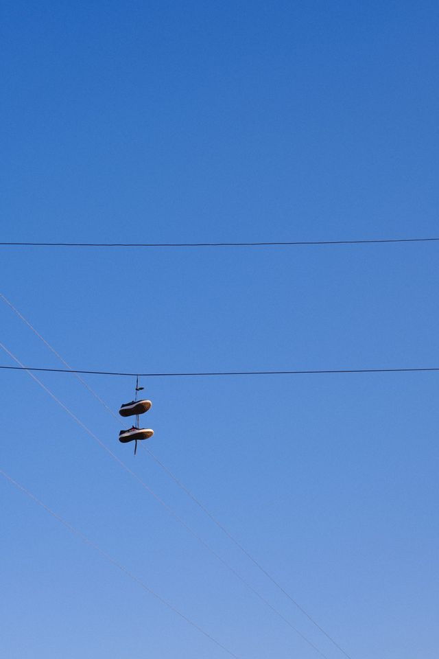 結ばれた靴が青空を背景に架空線から下がる。