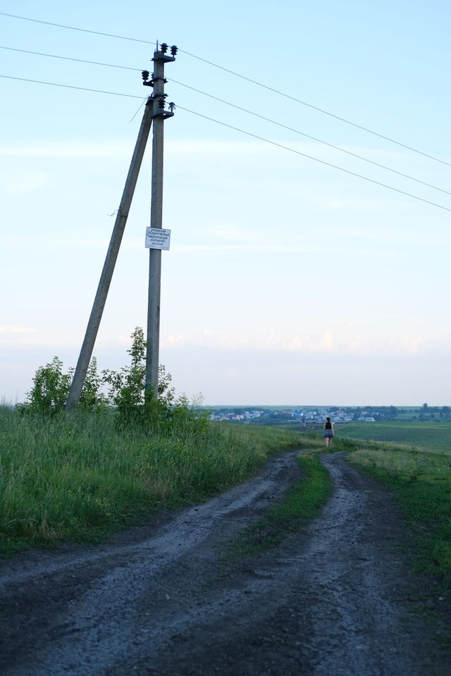 電柱に沿う田舎の未舗装路の先に小さな人影が見える。