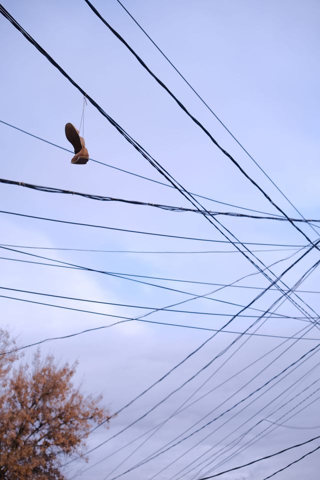 密集した架空線の中に吊られた靴が浮かび上がる。