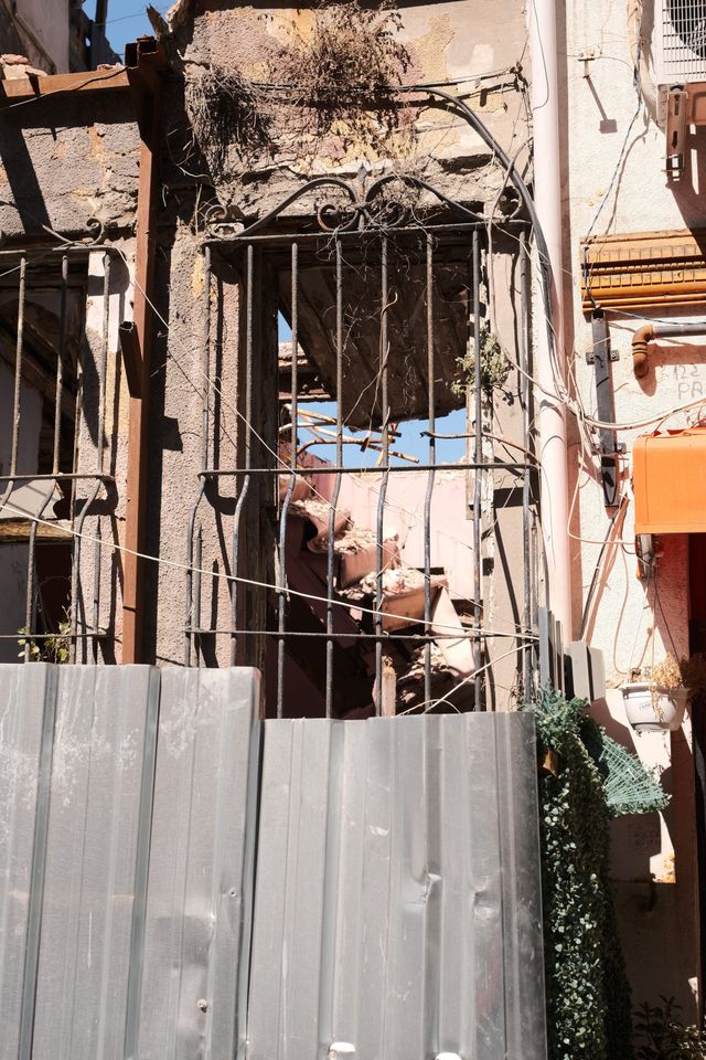 古びた建物の外側に配管、ケーブル、金属の手すりが密集する。